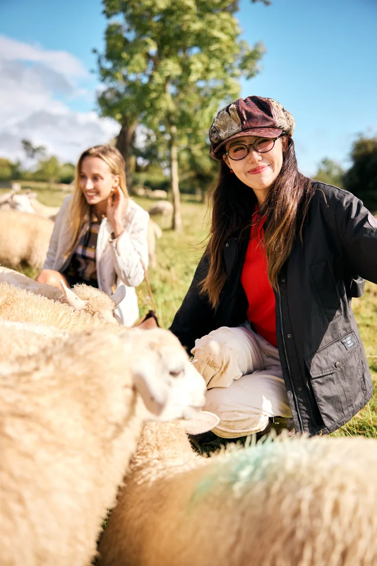 A Hazzys creator posing beside sheep during the outdoor activation