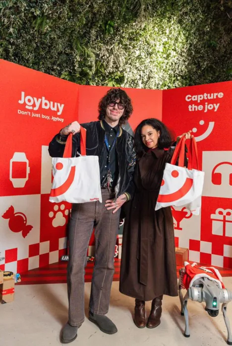 Guests posing with branded shopping bags inside the Joybuy pop-up